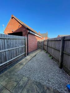 a driveway with a fence and a brick building at Silver Stag Properties, Comfy 2 BR Home in Ashby in Smisby