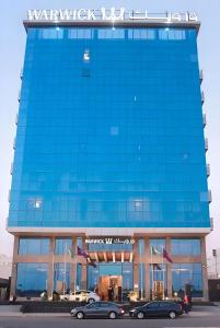 un edificio azul con coches estacionados frente a él en Warwick Hotel Jeddah en Yeda