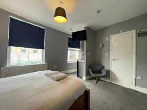 a bedroom with a bed and a chair and windows at Small Double Studio close to King's Cross & Camden in London