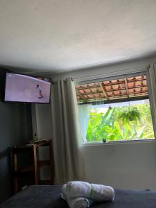 a bedroom with a window with a tv and a bed at Chalé Tiririca pé na areia in Itacaré