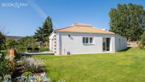 uma pequena casa branca com um quintal em Le Clos de Jade - Appt 3 étoiles avec piscine partagée em Pornic