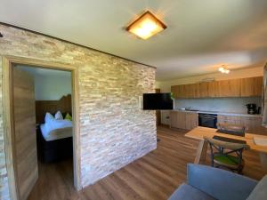 Il comprend un salon avec un mur en briques et une cuisine. dans l'établissement Ferienwohnungen Artenreitwinkl Hallinger, à Schönau am Königssee