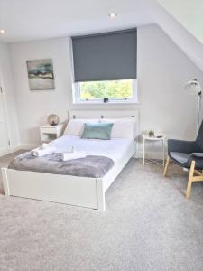 a white bedroom with a bed and a window at Hyland Apartment by CityNest in Chelmsford