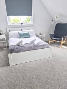 a bedroom with a bed and a chair and a window at Hyland Apartment by CityNest in Chelmsford