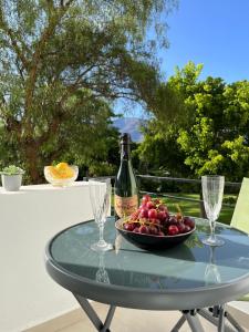 a glass table with a bottle of wine and a bowl of fruit at Golden Bay Apartment in Estepona