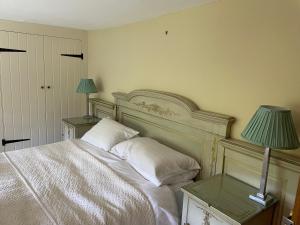 a bedroom with a white bed and two lamps at Bartley Mill Farmhouse in Wadhurst