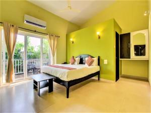 a bedroom with green walls and a bed and a window at FabEscape Vagator Retreat Resort With Swimming Pool in Goa Velha