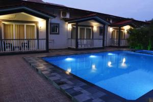 戈阿韦尔哈FabEscape Vagator Retreat Resort With Swimming Pool - Nr Vagator Beach的夜晚房子前的游泳池