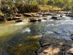 un ruisseau d'eau avec des rochers dans une rivière dans l'établissement Chalé Refúgio 2, 
