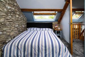 uma cama num quarto com uma parede de pedra em Converted Granary on a rural small holding em Cross Inn