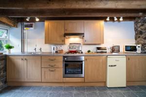 a kitchen with wooden cabinets and a white refrigerator at Converted Granary on a rural small holding in Cross Inn