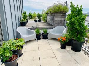 d'une terrasse avec des chaises blanches et des plantes en pot sur un balcon. dans l'établissement Penthouse avec climatisation, à Arcueil