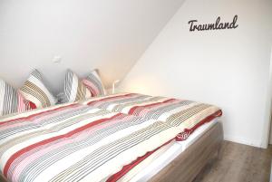 a bedroom with a bed with a striped comforter at Mien Dröm in Norddeich