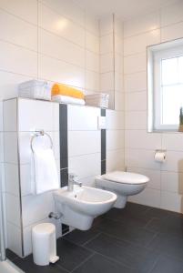 a white bathroom with a sink and a toilet at Mien Dröm in Norddeich