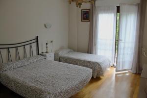 a bedroom with two beds and a window at Ikaztegietako Ostatua in Icazteguieta