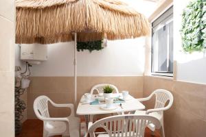 a table and chairs under a straw umbrella at Casa Centro Historico Barbate in Barbate +13 photos