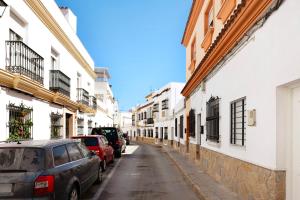 a narrow street with cars parked on the side at Casa Centro Historico Barbate in Barbate