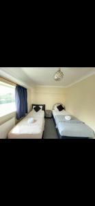 Duas camas num pequeno quarto com cortinas azuis em Comfy, cozy house with disabled access em St Ives