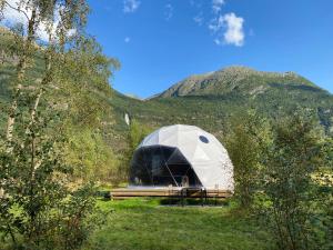 une grande tente en forme de dôme avec une montagne en arrière-plan dans l'établissement Olden Glamping - One with nature, à Stryn