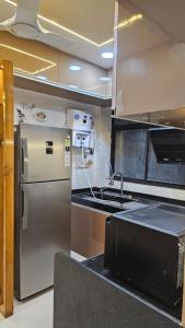 La cuisine est équipée d'un réfrigérateur en acier inoxydable et d'un évier. dans l'établissement Luxurious 2 BHK Apartment Fully Furnished with All Major Electronics and Automation, à Pune