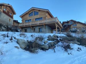 una casa de madera en la nieve con rocas delante en Chalet deS'AMY et sa terrasse pour 8/10 personnes, en Font-Romeu-Odeillo-Via