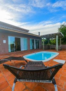 a patio with a pool and chairs and a house at Chalés Vila da Rosa in Ribeirão Claro