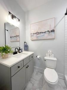 a bathroom with a toilet and a sink and a mirror at Elegant Duplex Steps to Forsyth! in Savannah