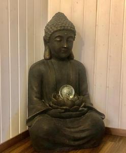a statue of a buddha sitting on the floor at 2 Zimmer mit Seeblick Bad geteilt auf der Etage in Kilchberg