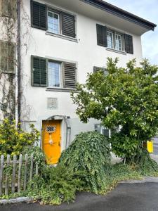 a white house with a yellow door and a fence at 2 Zimmer mit Seeblick Bad geteilt auf der Etage in Kilchberg