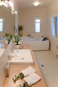 a white bathroom with a sink and a tub at Lia beach Estate in Mikonos