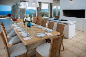 a dining room with a long table with chairs at Lia beach Estate in Mikonos