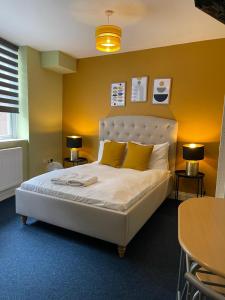 a bedroom with a large white bed with yellow walls at King's Cross Bright Studio in London