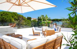 eine Terrasse mit weißen Möbeln und einem Sonnenschirm in der Unterkunft Awesome Apartment In Pineto With Outdoor Swimming Pool, Wifi And 2 Bedrooms in Pineto