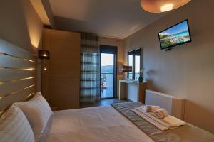 Schlafzimmer mit einem Bett und einem TV an der Wand in der Unterkunft Athos Thea Luxury Rooms in Sarti