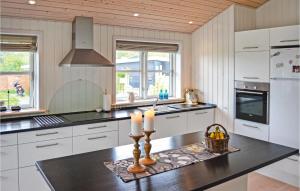 フレデリクスハウンにあるAmazing Home In Frederikshavn With 3 Bedrooms And Wifiの白いキャビネットとカウンターにキャンドル2本が備わるキッチン