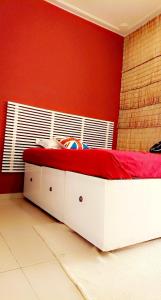 1 dormitorio con cama blanca y pared roja en Lajungle Muyenga, en Kampala