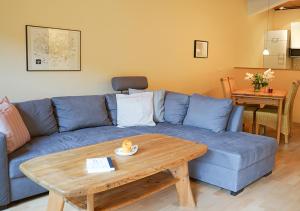 a living room with a blue couch and a wooden table at Ferienhof Landlord in Fehmarn