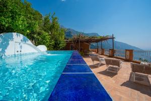 a swimming pool with blue water and chairs and mountains at Villa Ambra Positano in Positano