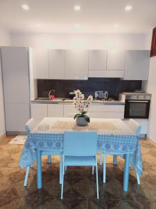 eine Küche mit einem Tisch mit blauen Stühlen und einer Vase mit Blumen in der Unterkunft Casa di Nzino in Guglionesi