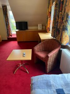 a hotel room with a chair and a table at Hotel Strand-Café in Roßbach