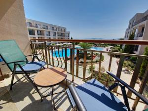 a balcony with chairs and a table and a swimming pool at Diamond Beach Sarafovo by KP in Burgas City