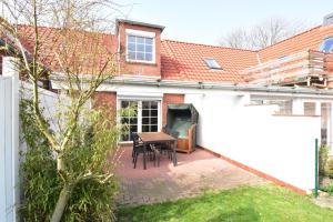 um pátio com uma mesa e cadeiras numa casa em Sonnenwind am Norddeich em Norddeich