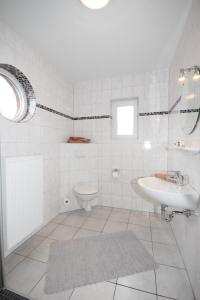 een witte badkamer met een wastafel en een toilet bij Lee in Norddeich