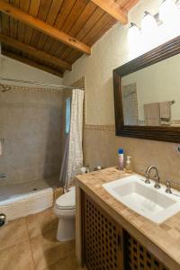 a bathroom with a sink and a toilet and a mirror at Luxurious Lake Front Propertyfamiliescouples in Cerro de Oro