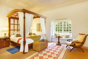a bedroom with a bed and a chair and a window at The Oberoi Rajvilas Jaipur in Jaipur
