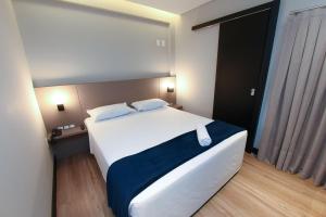 a bedroom with a large white bed with a blue blanket at Arco do Sol Park Hotel in Camboriú