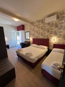 a hotel room with two beds and a desk at Hotel Liu in Lido di Camaiore