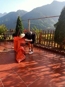 a person bending over on a patio with mountains in the background at Lee's Charm Homestay in Sa Pa