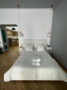 a bedroom with a white bed with two towels on it at Oyster Flat Victoriei in Bucharest