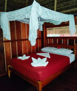 - un lit avec 2 oreillers et une couverture rouge dans l'établissement WaitaAmazonlodge, 